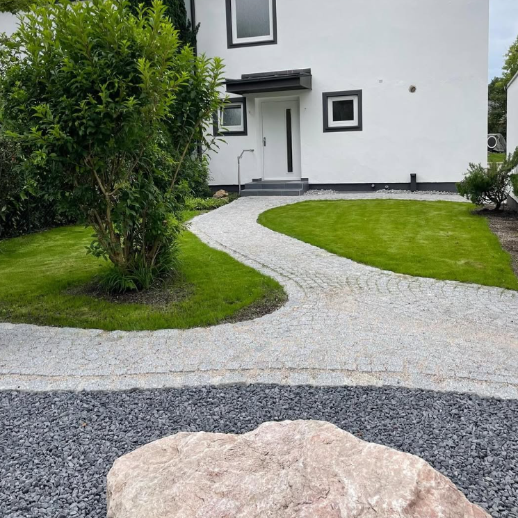 Sorgfältig gepflasterter Gartenweg neben frischem Rasen, Landschaftsbau von Isartaler Garten GbR aus Bad Tölz.